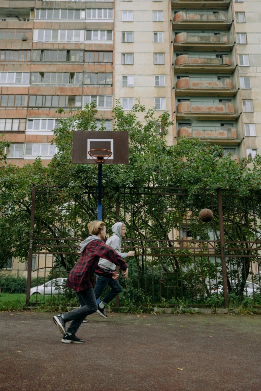 two men playing basketball on the side of a street