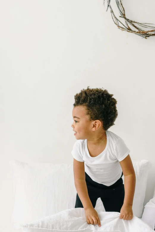 a little girl standing on top of a bed, dressed in a white t shirt, black man with afro hair, zoomed in, sitting on a couch