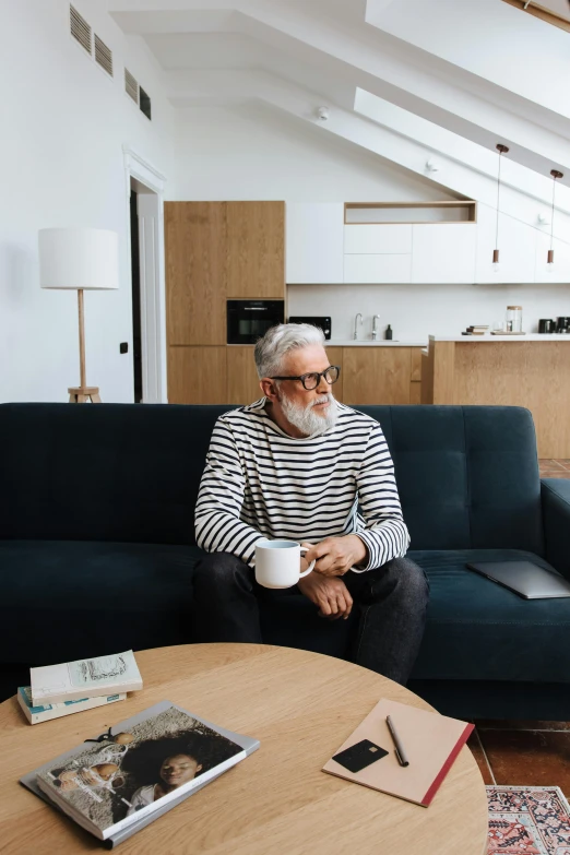 a man sitting on a couch in a living room, pexels contest winner, white beard, wearing stripe shirt, scandinavian design, morning coffee