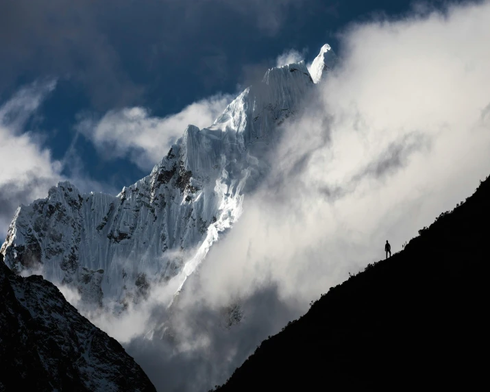 a person standing on top of a snow covered mountain, by Peter Churcher, unsplash contest winner, hurufiyya, nepal, towering cumulonimbus clouds, profile image, tall spires