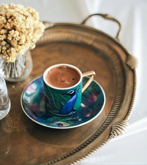 a close up of a cup of coffee on a tray, by Meredith Dillman, hurufiyya, peacock colors, chocolate, thumbnail, turkey