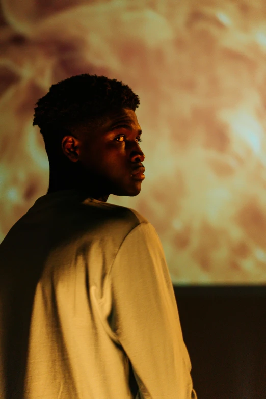 a man standing in front of a projector screen, by Maxwell Bates, trending on unsplash, realism, black teenage boy, looking to his side, a stunning young ethereal figure, ( ( theatrical ) )