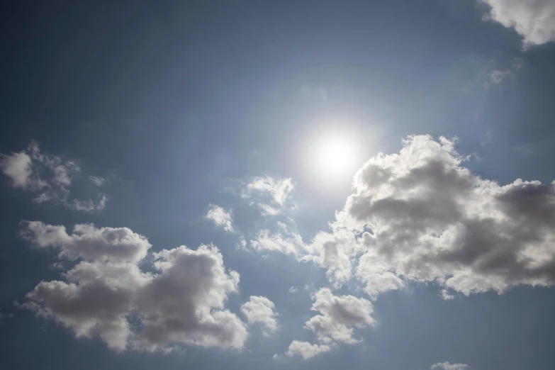 the sun is shining through the clouds in the blue sky, by Bertram Brooker, pexels, light and space, light source from the left, hot summer day, loots of clouds, giant sun