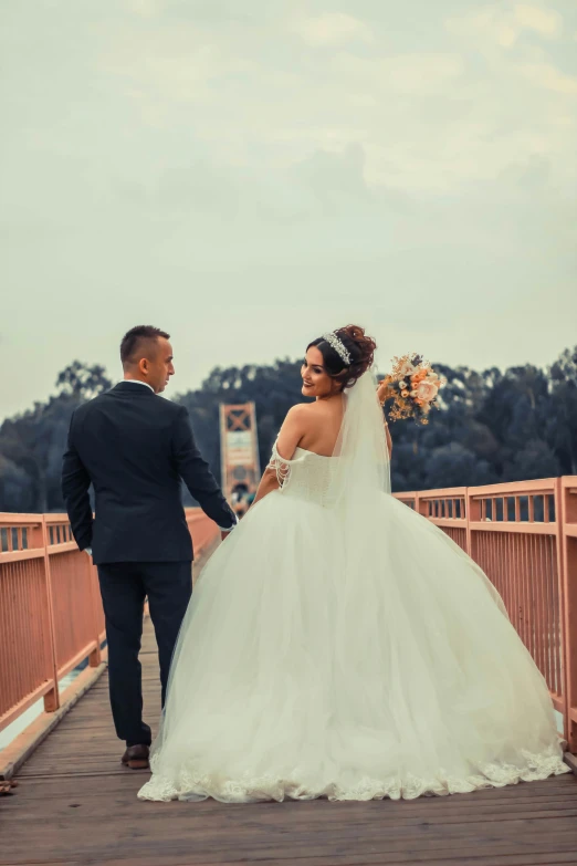 a bride and groom walking across a bridge, by Charly Amani, formal wear, couple dancing, realistic photo”