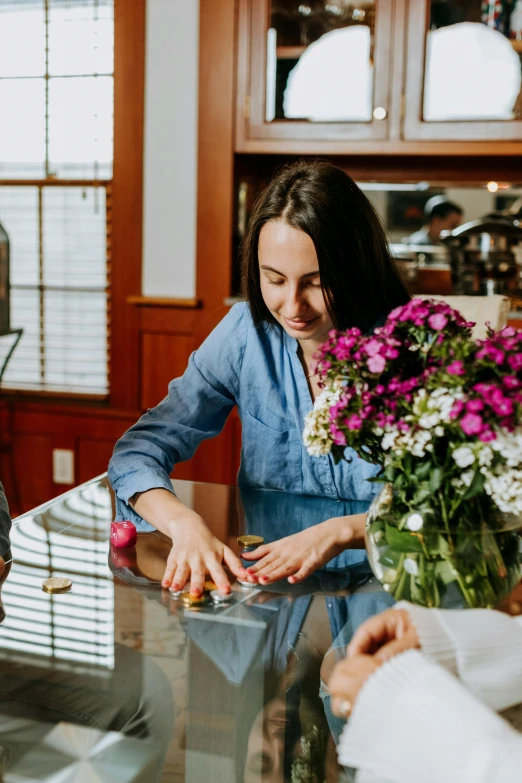 a group of people sitting around a glass table, woman in flowers, kitchen counter, family friendly, emily rajtkowski