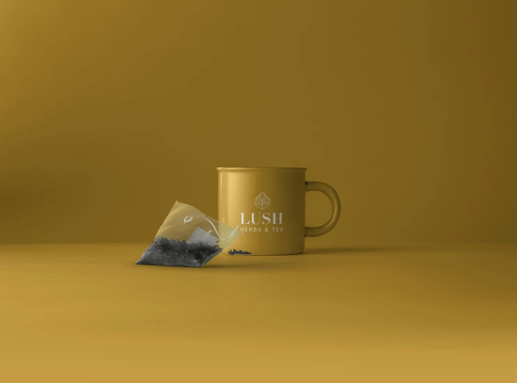 a cup of tea next to a tea bag, a 3D render, inspired by Tōshi Yoshida, featured on unsplash, unrefined sparkling gold nugget, lush, yellow charcoal, minimalist logo without text
