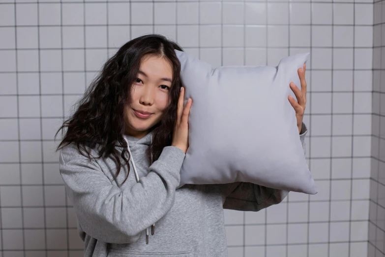 a woman holding a pillow in front of her face, inspired by Sarah Lucas, unsplash contest winner, flat grey color, product view, square, half asian
