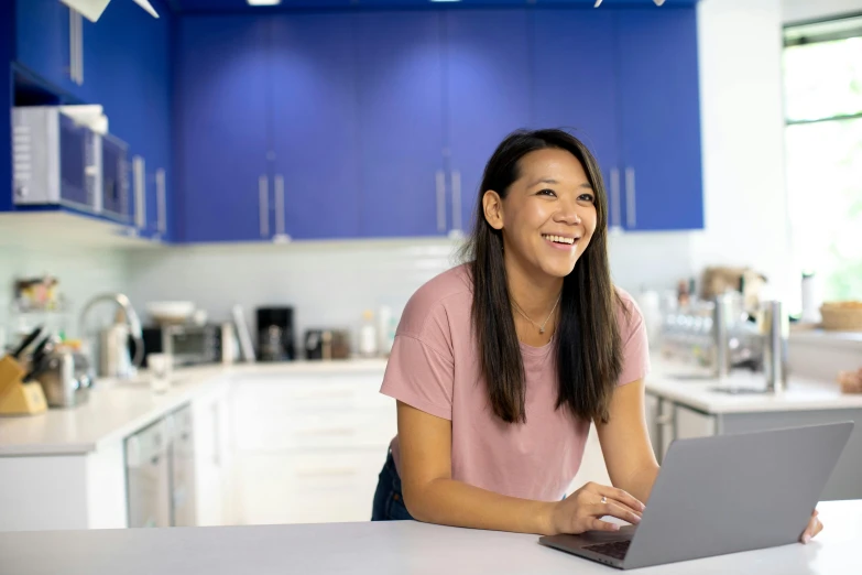 a woman sitting at a kitchen counter with a laptop, inspired by helen huang, smiling playfully, avatar image, unblur, commercial photo