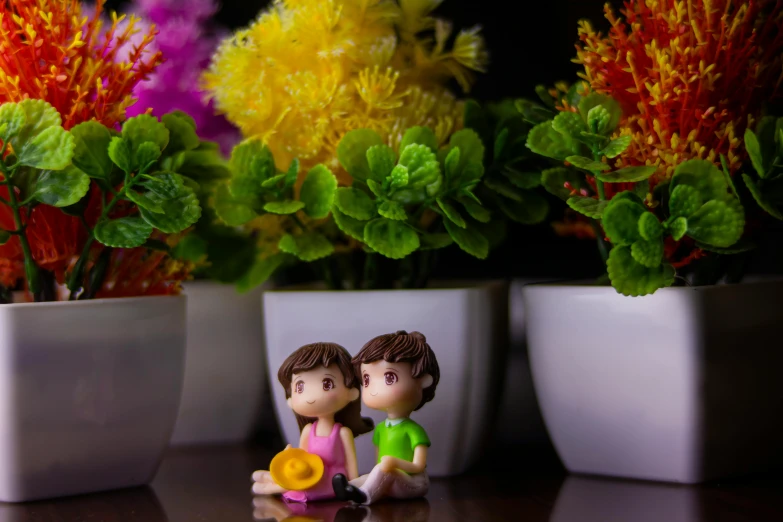 a couple of figurines sitting on top of a table, a picture, by Lilia Alvarado, pexels contest winner, floral flowers colorful, cute boys, avatar image, potted plant