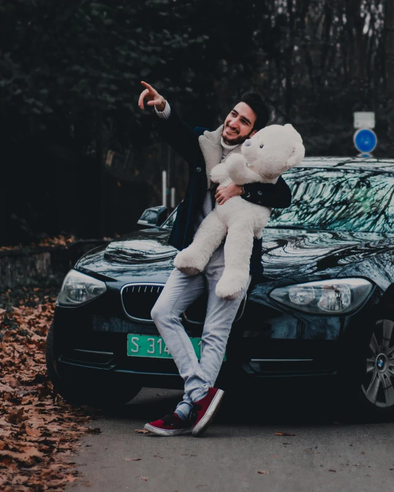 a man sitting on top of a car holding a teddy bear, by Sebastian Spreng, pexels contest winner, non-binary, 🚿🗝📝, modelling, hugging