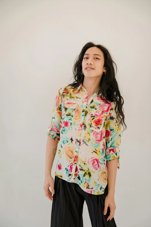 a woman standing in front of a white wall, an album cover, by Olivia Peguero, trending on unsplash, renaissance, wearing yellow floral blouse, button - up shirt, pastel roses, qi sheng luo