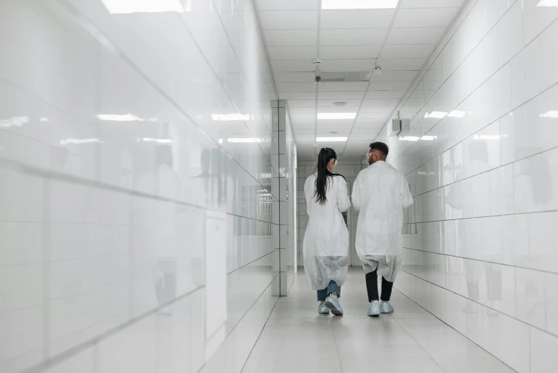 a couple of people walking down a hallway, pexels, antipodeans, wearing lab coat, sterile minimalistic room, surgeon, industry