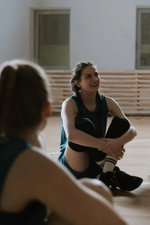 a group of women sitting on top of a wooden floor, in a gym, greta thunberg smiling, overlay, sports setting