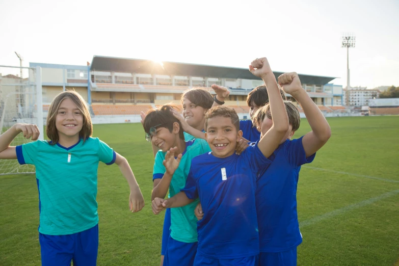 a group of children standing on top of a soccer field, a picture, shutterstock, all overly excited, exterior shot, in the evening, game ready