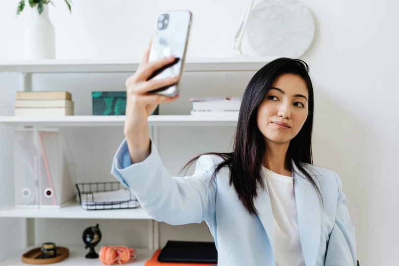 a woman taking a selfie with her cell phone, trending on pexels, wearing lab coat and a blouse, avatar image, asian women, office clothes