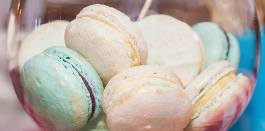 a glass filled with macarons sitting on top of a table, a pastel, by Adam Marczyński, trending on unsplash, rococo, steamed buns, 15081959 21121991 01012000 4k, an extreme closeup shot, thumbnail