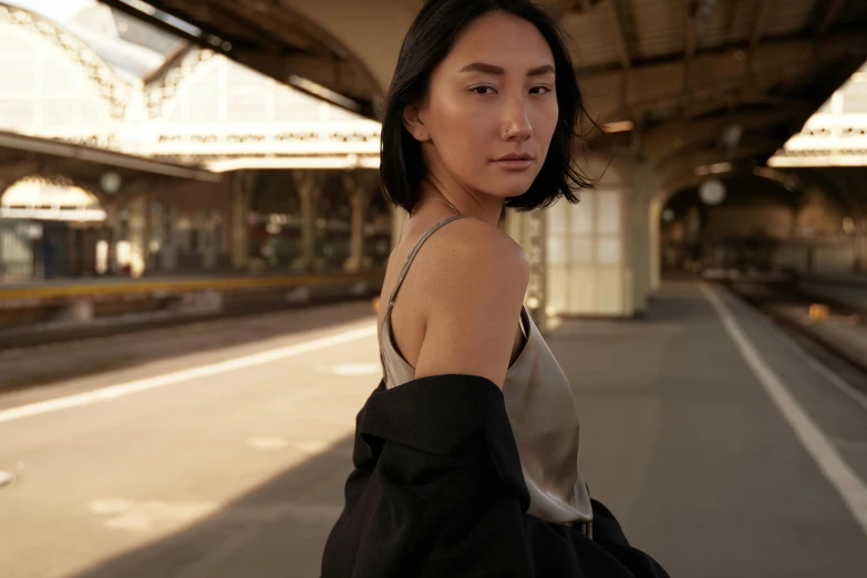 a woman standing in the middle of a train station, inspired by Yuko Tatsushima, trending on pexels, photorealism, wearing black camisole outfit, photoshoot for skincare brand, medium format. soft light, wearing acne outfit