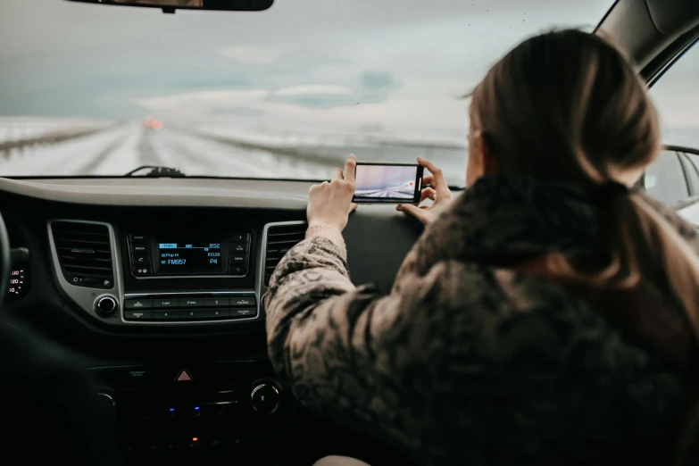 a woman using a cell phone while driving a car, a picture, trending on pexels, happening, square, iceland photography, avatar image, behind the scenes photo