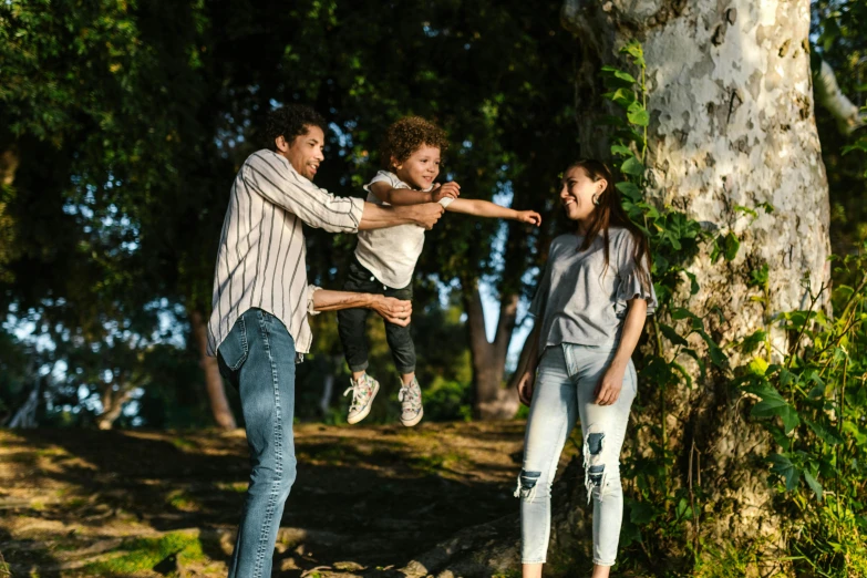 a group of people standing next to a tree, pexels contest winner, figuration libre, families playing, portrait of family of three, jumping, [ cinematic