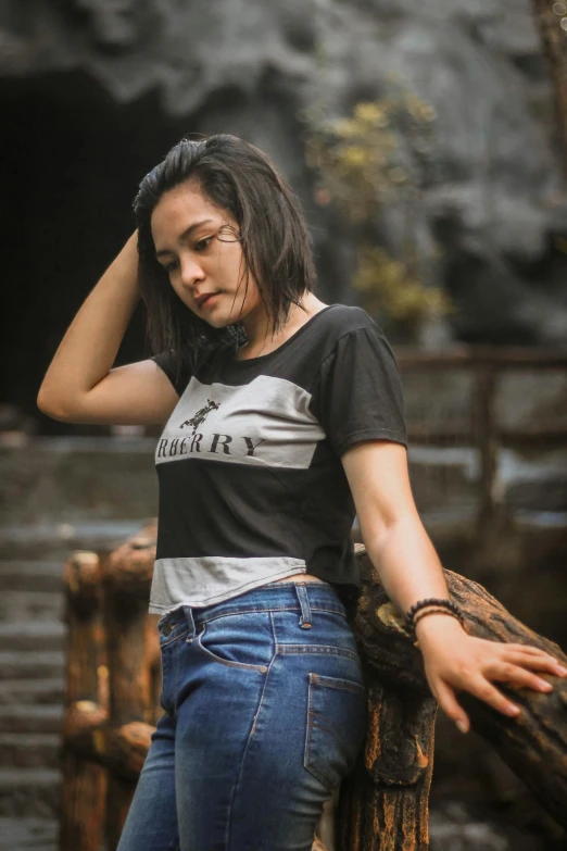 a woman in a black and white shirt leaning on a wooden fence, inspired by Rudy Siswanto, hurufiyya, avatar image, jeans and t shirt, 5 0 0 px models, black t-shirt