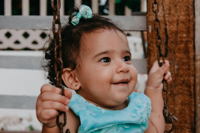 a close up of a child on a swing, pexels contest winner, hurufiyya, brown and cyan color scheme, babies in her lap, smiling confidently, mixed race