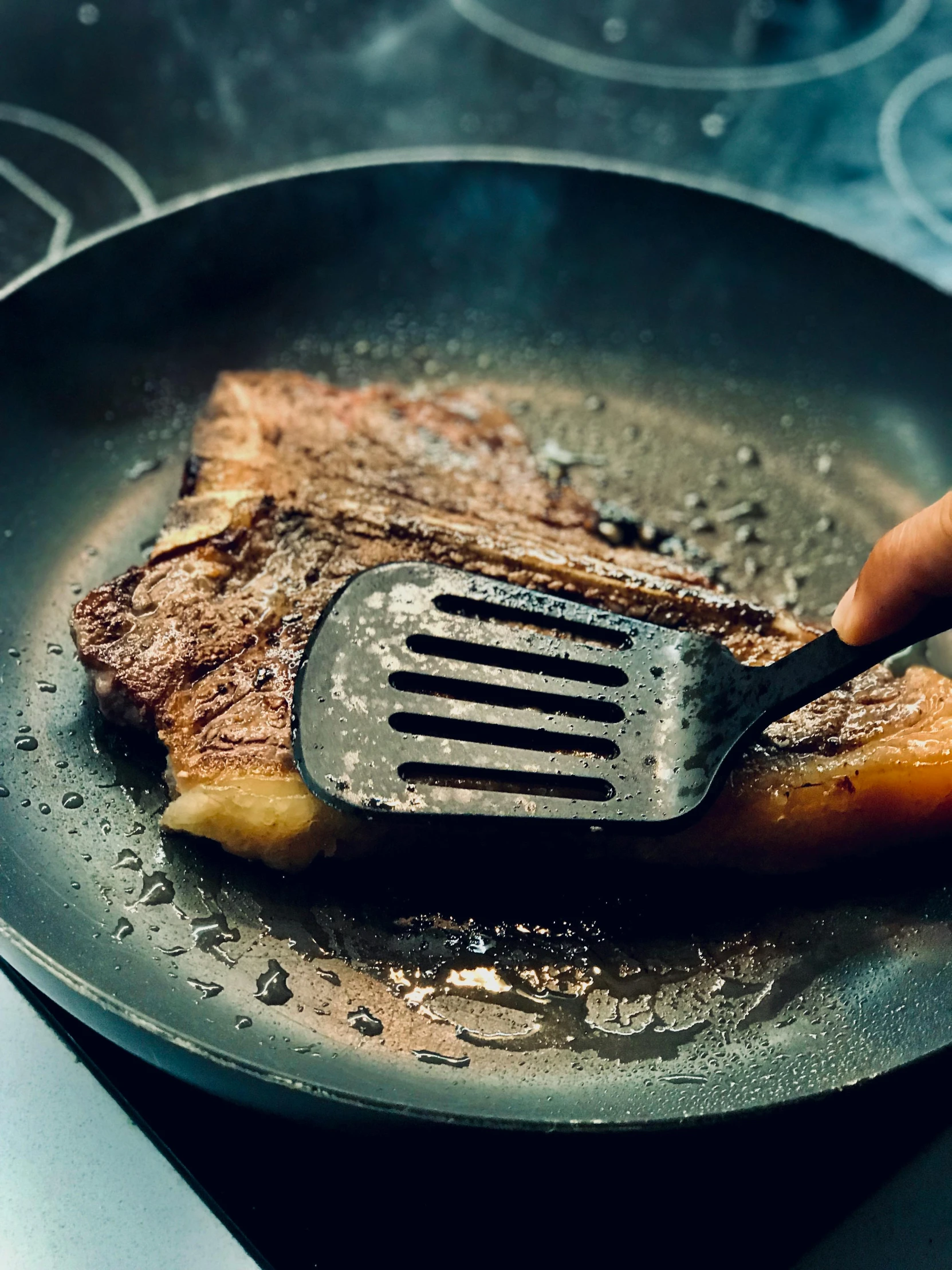 a steak being cooked in a frying pan with a spatula, by Joe Bowler, gloss finish, alessio albi, plated arm, battered