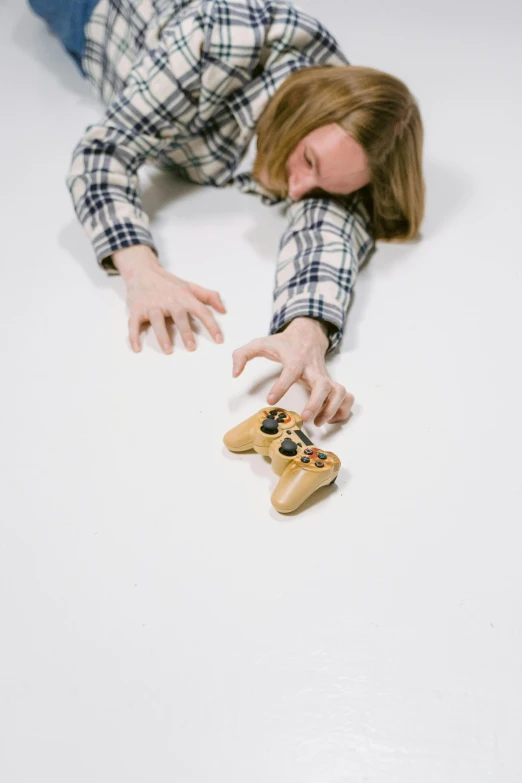 a woman laying on the floor playing a video game, inspired by Sarah Lucas, unsplash, hyperrealism, hand model, broken toys, controller, low quality photo