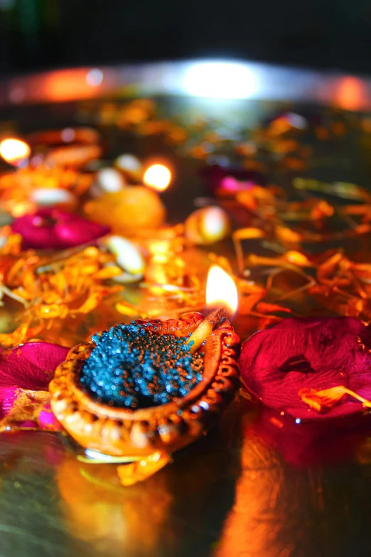 a bowl filled with candles and flowers on top of a table, hindu ornaments, bright blue glowing water, confetti, vivid)