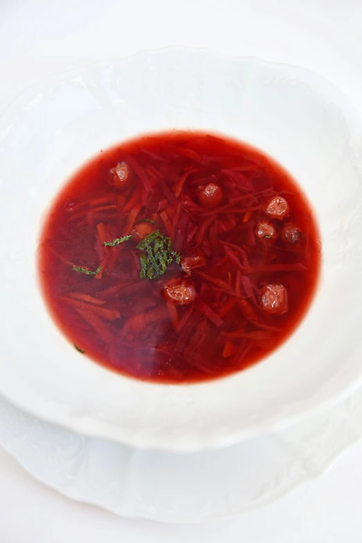 a bowl of soup sitting on top of a white plate, inspired by Géza Dósa, renaissance, in crimson red, anastasia ovchinnikova, jelly, pork