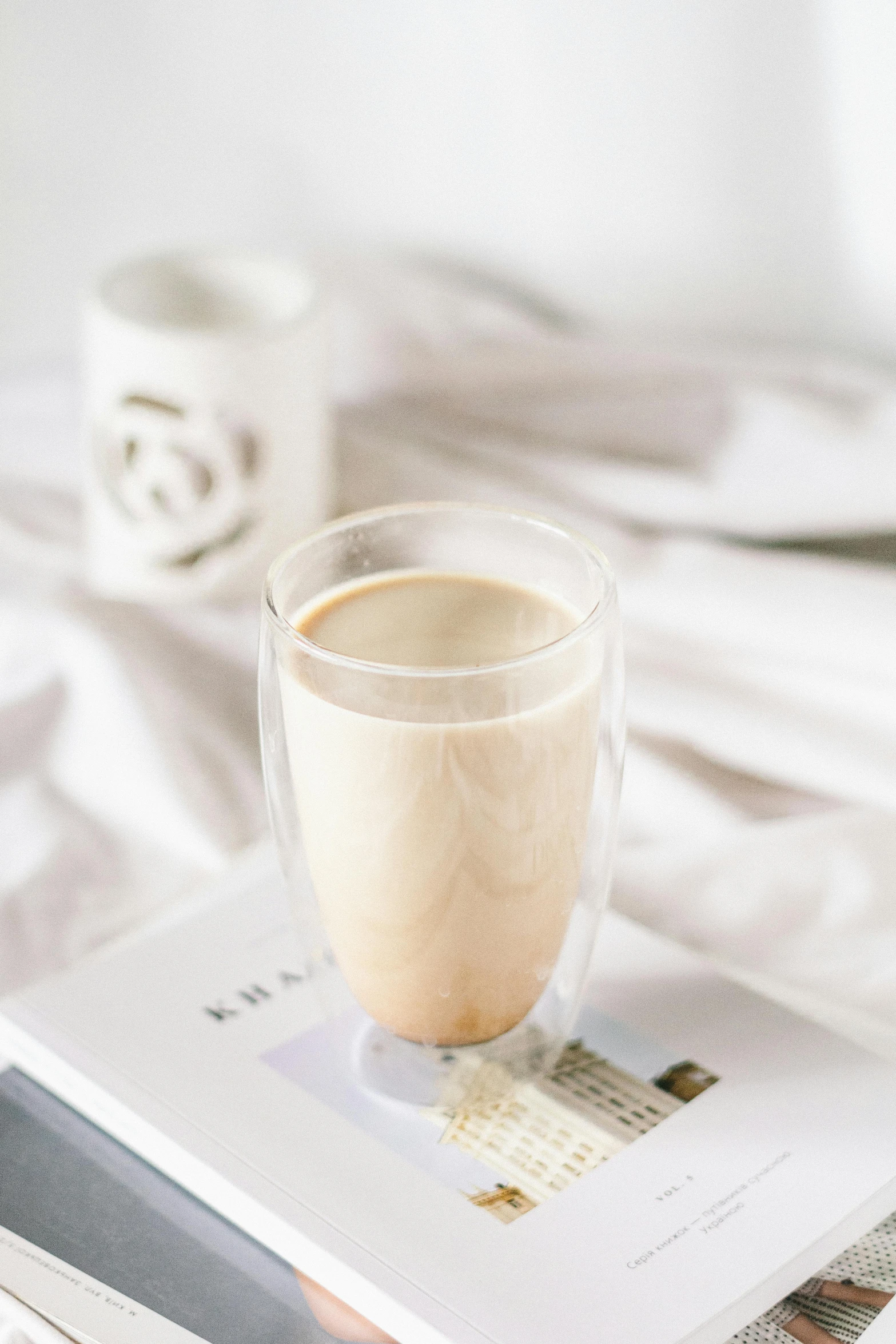 a cup of coffee sitting on top of a book, vanilla smoothie explosion, diffused natural skin glow, thumbnail, understated