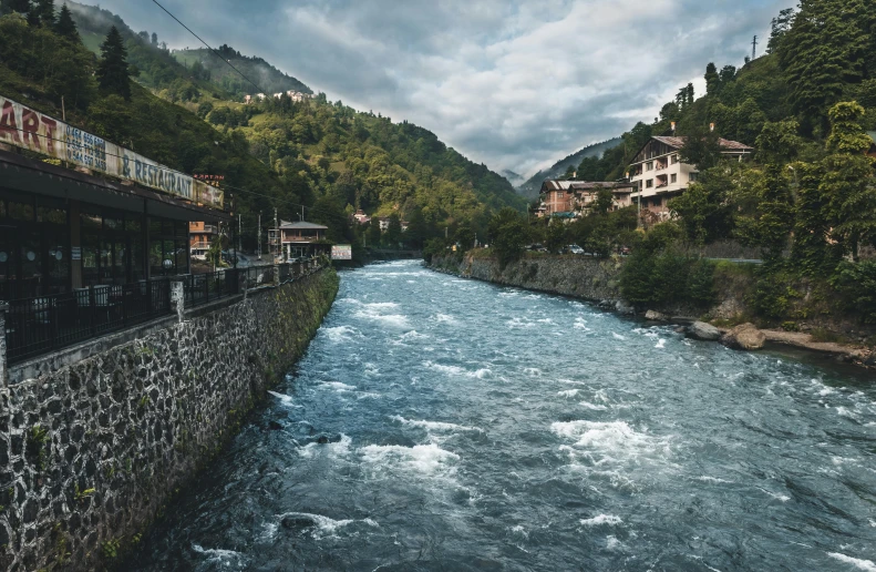 a river running through a lush green forest covered hillside, by Muggur, pexels contest winner, hurufiyya, running through italian town, violent stormy waters, a wooden, a handsome