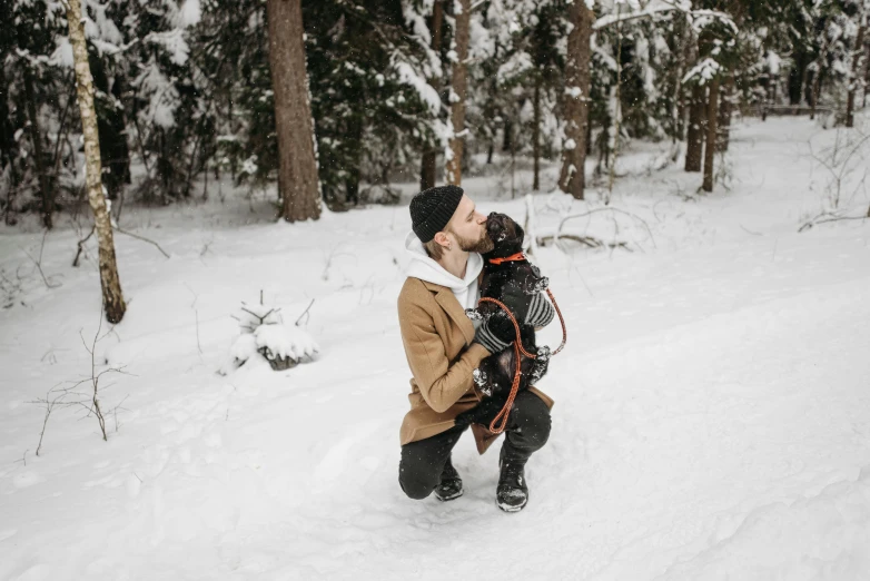 a man and his dog playing in the snow, by Jaakko Mattila, pexels contest winner, hugging and cradling, romantic lead, black, tan