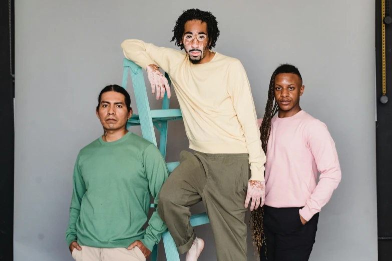 a group of three men standing next to each other, inspired by Pablo Rey, antipodeans, wearing a green sweater, light skin tone, pastelwave, brown skin