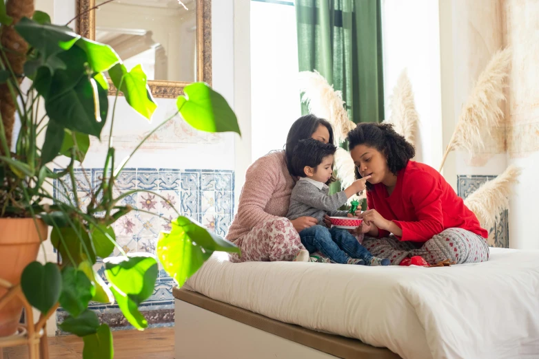 a woman and two children sitting on a bed, pexels contest winner, samsung smartthings, red and green color scheme, hispanic, location in a apartment