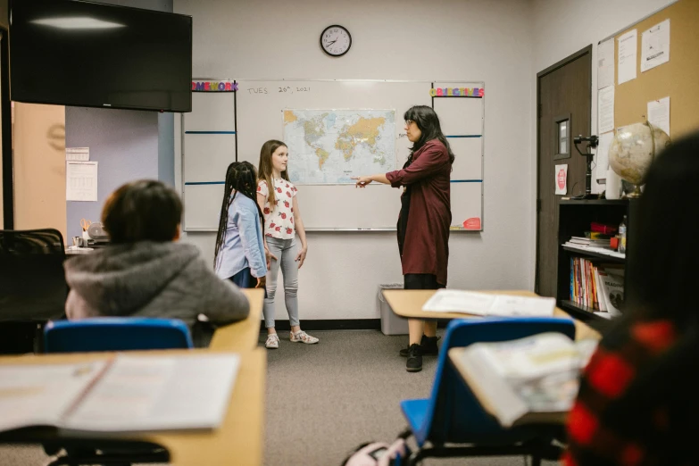 a woman teaching a class of children in a classroom, trending on unsplash, vancouver school, pokimane, standing in corner of room, national geographics, production photo