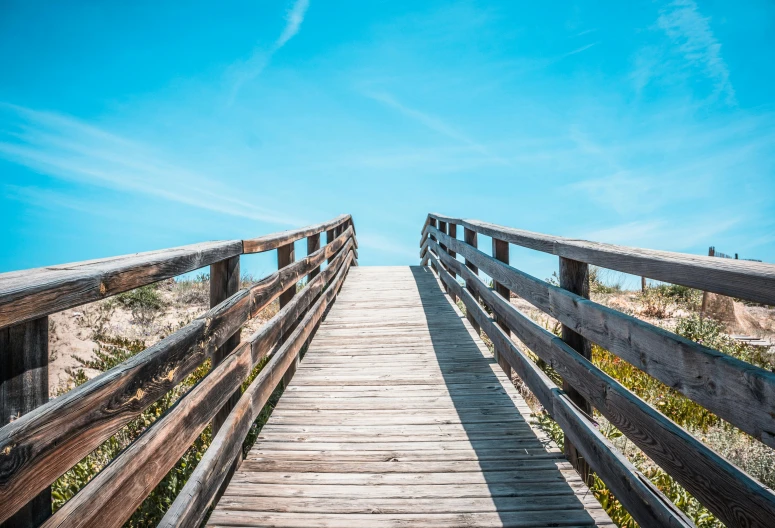 a wooden bridge leading to the beach, by Niko Henrichon, unsplash, happening, clear blue sky, 2 5 6 x 2 5 6 pixels, stairways, low angle 8k hd nature photo