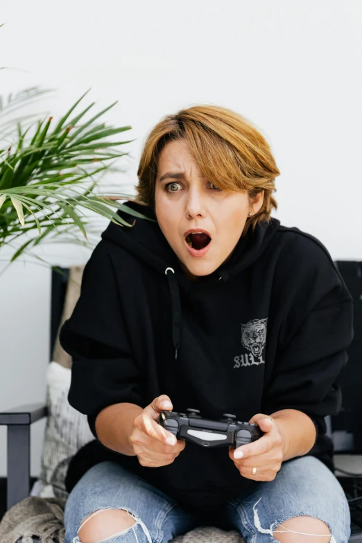 a woman sitting on a couch holding a video game controller, pexels contest winner, realism, shocked expression, tomboy, instagram story, hunting