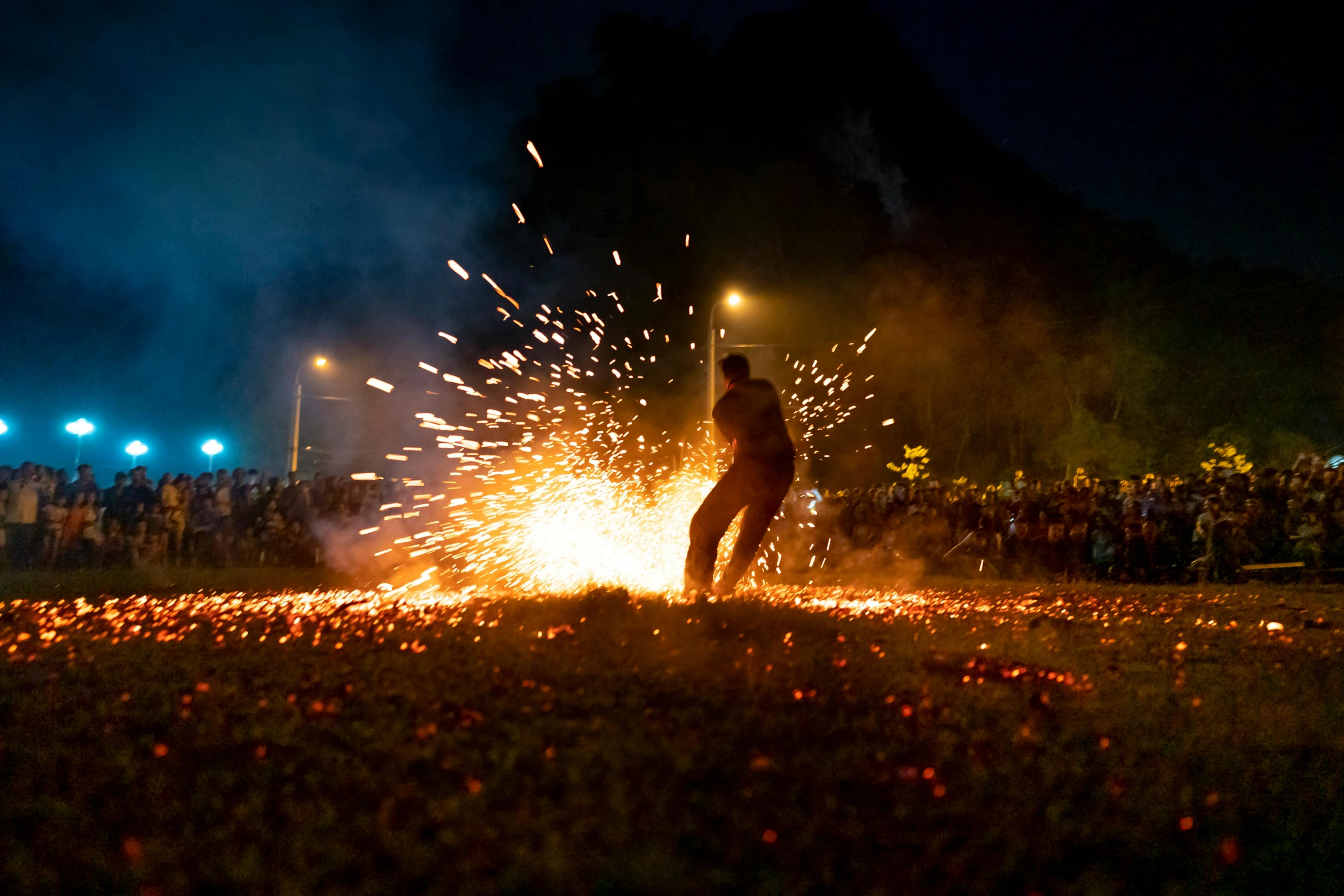 a man that is standing in the grass with a fire, by Niko Henrichon, pexels contest winner, happening, fireworks, avatar image, ceremonial ritual, college