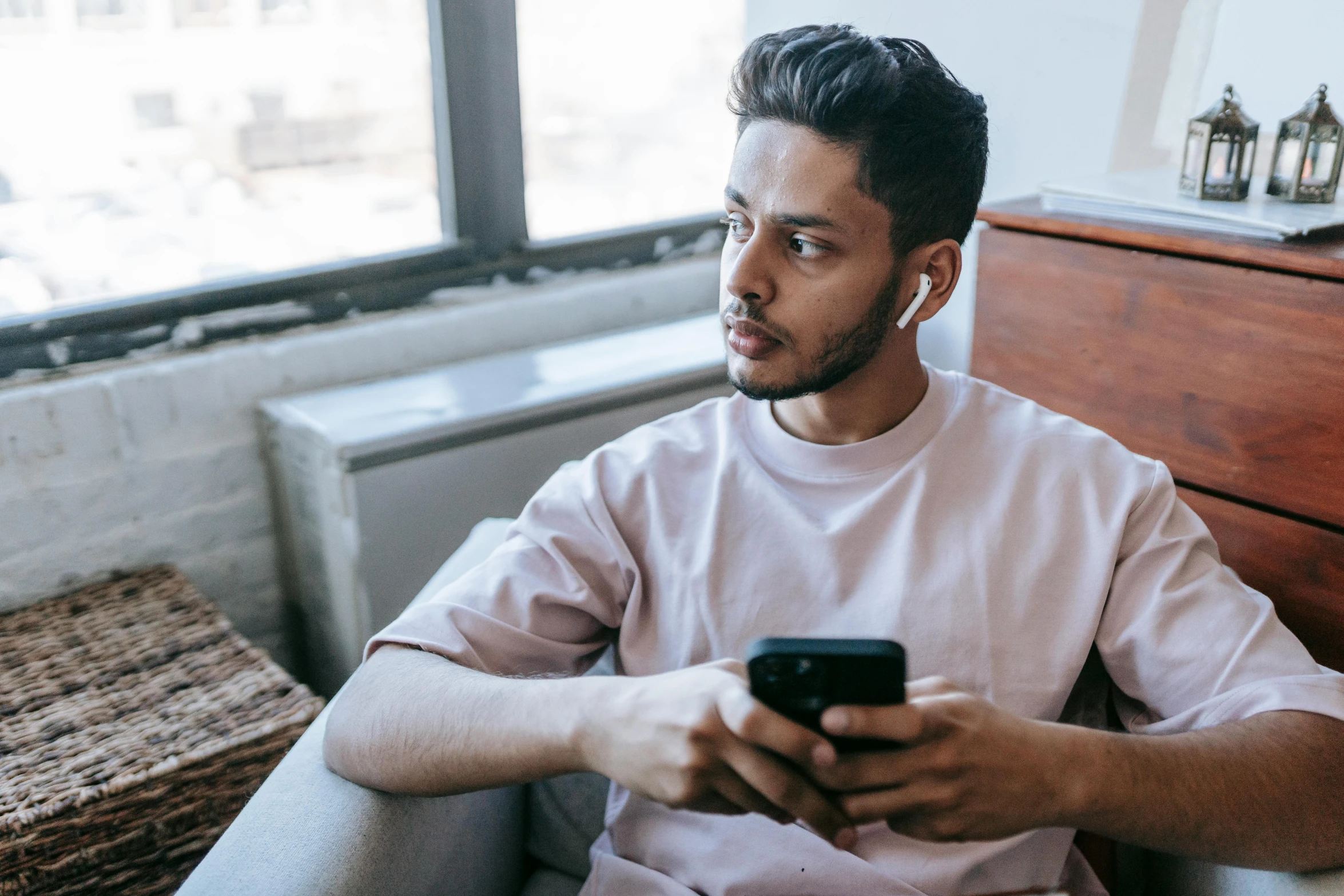 a man sitting in a chair looking at his cell phone, trending on pexels, lgbtq, earbuds, middle eastern skin, looking at monitor