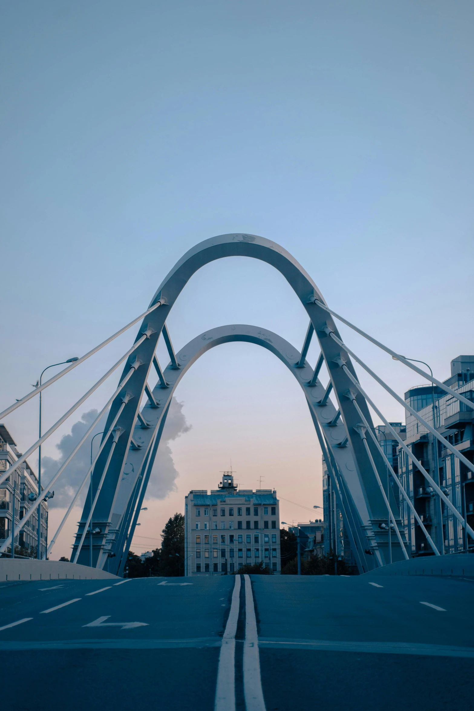 a bridge over a street with buildings in the background, inspired by Zaha Hadid, unsplash contest winner, rostov, sweeping arches, symmetric!, evening time