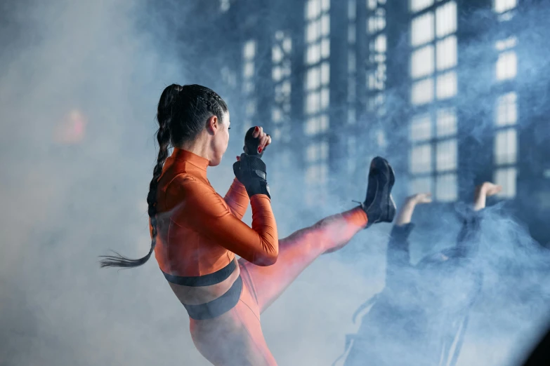 a woman in an orange outfit kicking a kick, pexels contest winner, figuration libre, photograph of a techwear woman, performance, hand wraps, smoke grenade