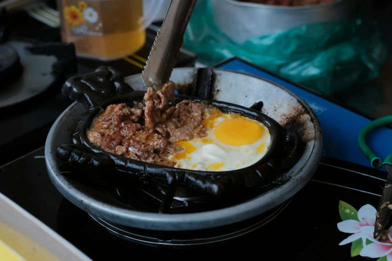 a frying pan filled with food sitting on top of a stove, dau-al-set, 王琛, eggs, crackling black lightning, manila