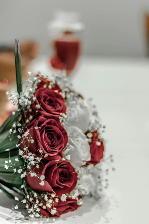 a close up of a bouquet of flowers on a table, maroon and white, close up photograph, angled shot, red rose