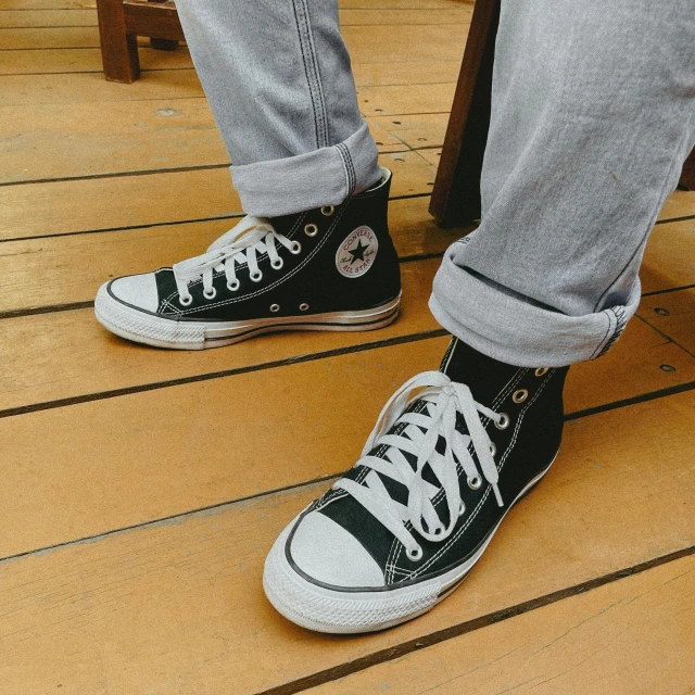 a close up of a person's shoes on a wooden floor, trending on pexels, photorealism, converse, wearing pants, black and white color aesthetic, (extremely detailed