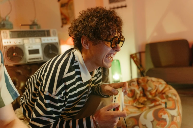 a man in striped shirt playing a video game, an album cover, inspired by Leo Leuppi, pexels contest winner, zack de la rocha, at home, betty la fea, high quality photo