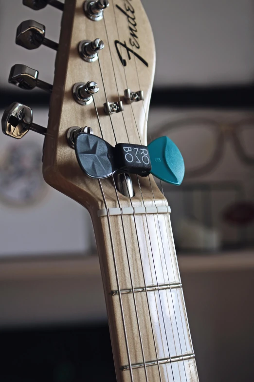 a close up of the headstock of a guitar, by Jason Benjamin, dada, teal, small gadget, over-shoulder shot, grey