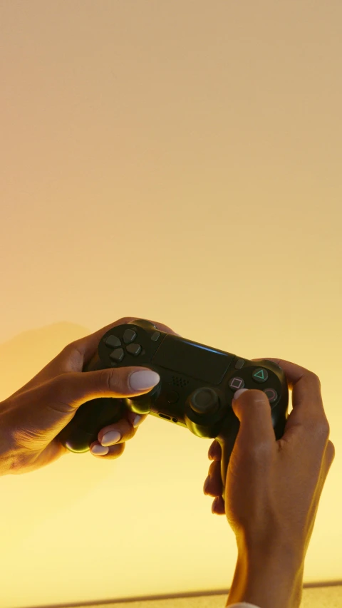 a person holding a video game controller in their hand, by Carey Morris, pexels, conceptual art, orange sky, square, ps 4 gameplay, yellow lighting from right