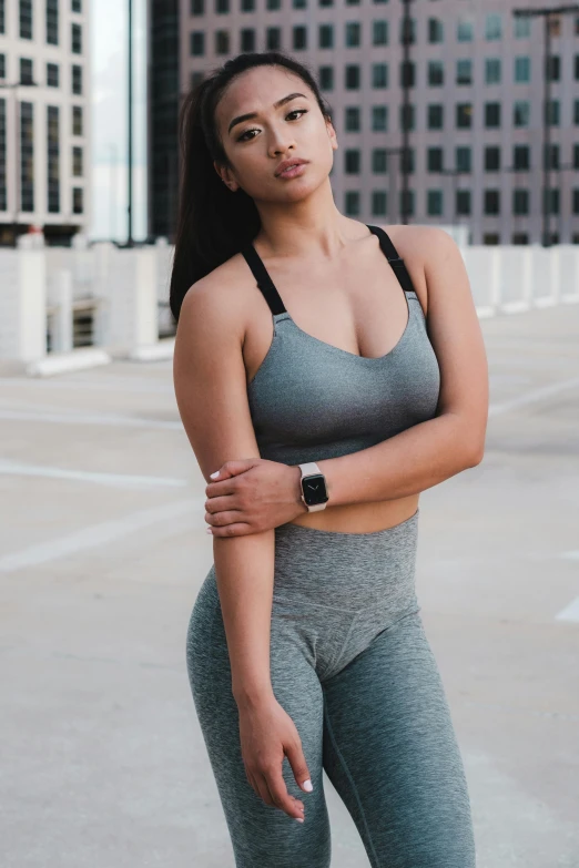a woman standing in the middle of a parking lot, inspired by Natasha Tan, trending on pexels, detailed sports bra, in gunmetal grey, thick set features, mid view