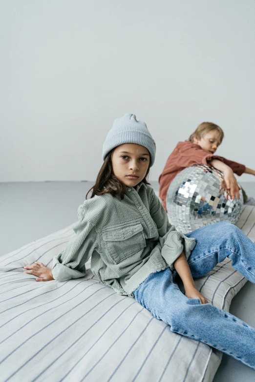 a couple of kids sitting on top of a bed, by Nina Hamnett, trending on unsplash, visual art, baggy clothing and hat, silver and muted colors, softplay, denim