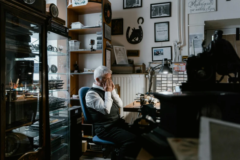 a man sitting in a chair talking on a cell phone, by Konrad Witz, pexels contest winner, silver very ornate jewelry, working in an office, cabinet of curiosities, a silver haired mad